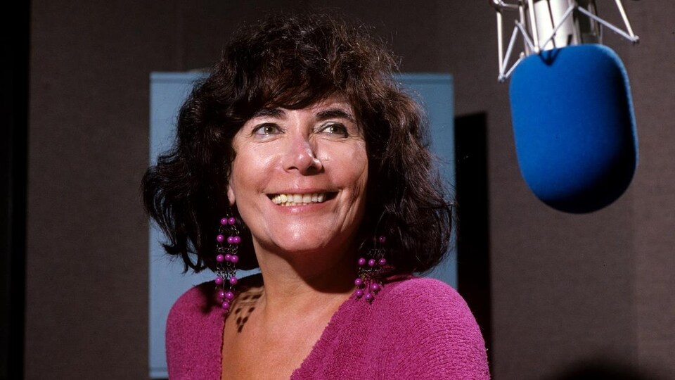 Minou Petrowski posant près d'un micro dans le studio 22 de la Maison de Radio-Canada.