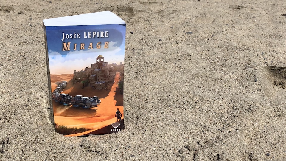 Il libro sta nella sabbia.  In copertina, possiamo vedere una città circondata dalla sabbia e una specie di treno metallico che la circonda.