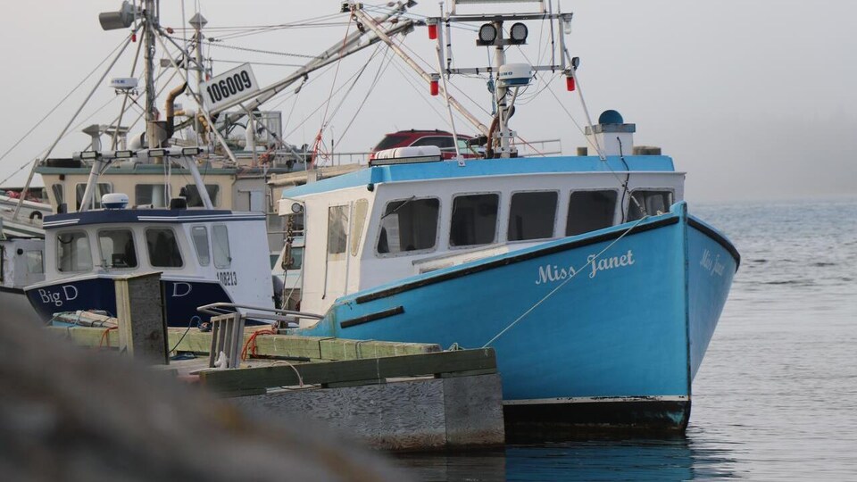 Un bateau de pêche peint en bleu et baptisé Miss Janet est amarré au quai.