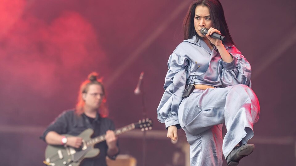 Mitski on stage, sings into the microphone.