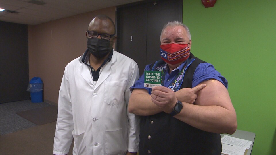 David Chartrand est pris en photo avec un certificat indiquant «j'ai reçu le vaccin contre la COVID-19», accompagné d'un médecin.