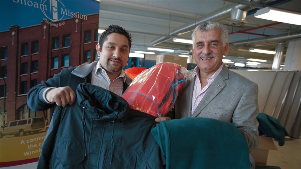 Albert El Tassi, à droite, et son fils Mohamed distribuent des sacs de couchage, des couvertures et des parkas.