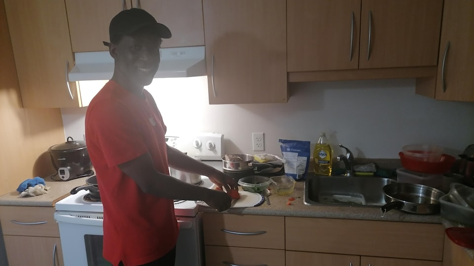 Mohamed Meite prépare de la nourriture sur son comptoir de cuisine.