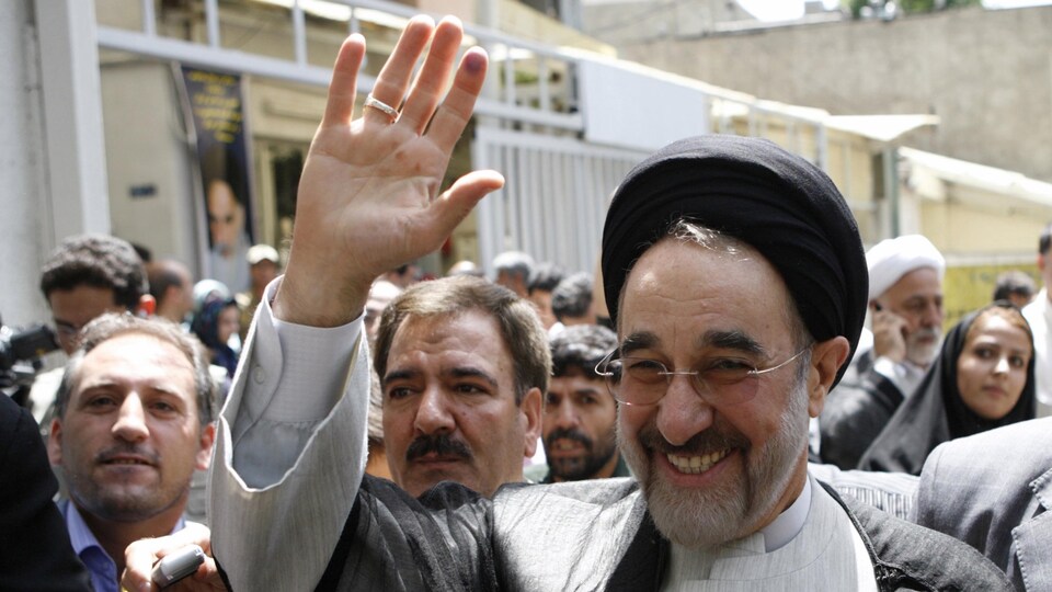 L'ancien président iranien Mohammad Khatami lève la main devant une foule.