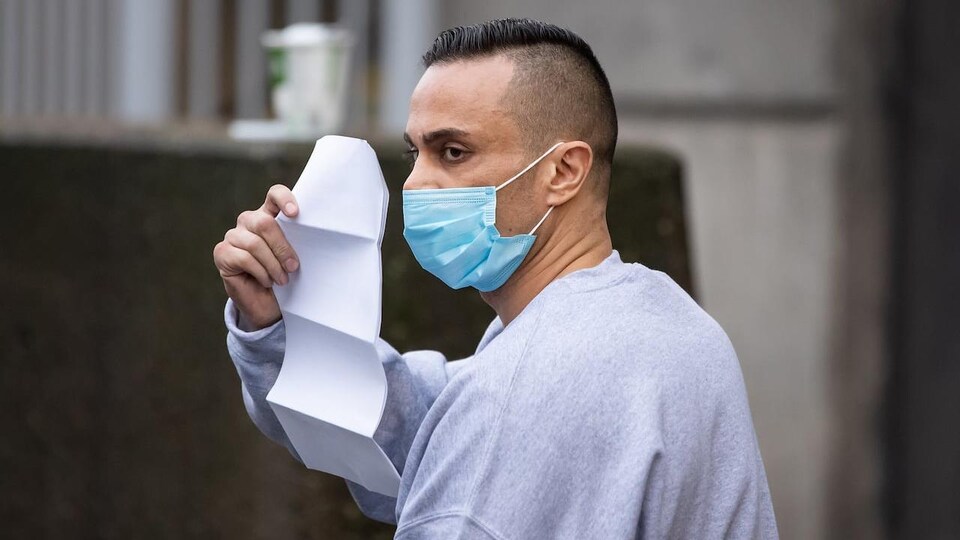 Mohammad Movassaghi porte un masque et tient une lettre dans une main.