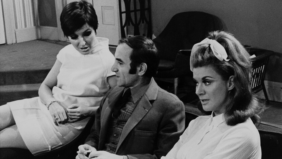 Dominique Michel, Charles Aznavour et Denise Filiatrault assis sur un divan.
