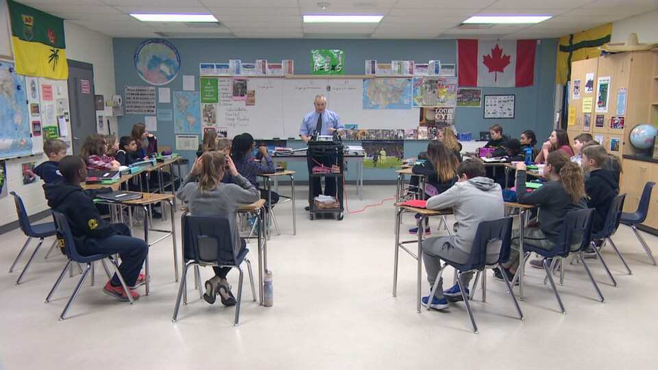 Une vingtaine d'élèves sont assis en classe devant leur professeur de français