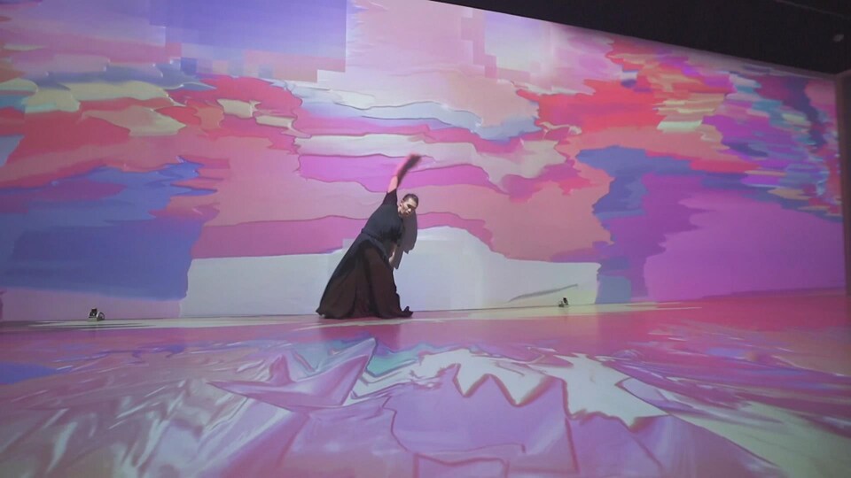 Un danseur seul sur scène entouré de projections psychédéliques.