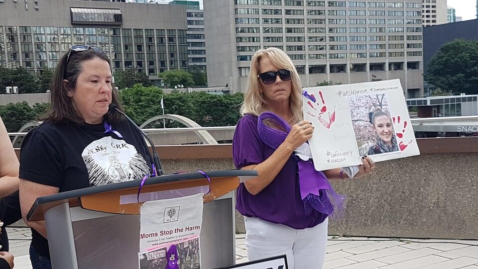 Deux femmes s'adressent à des gens devant un pupitre à Toronto. 