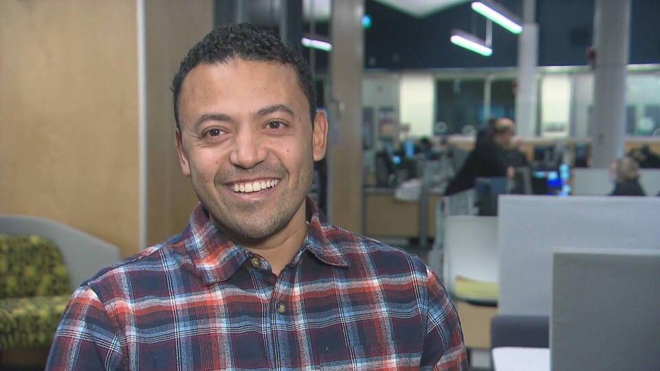 Moncef Lakouas, souriant, près de cubicules dans un bureau de Radio-Canada.