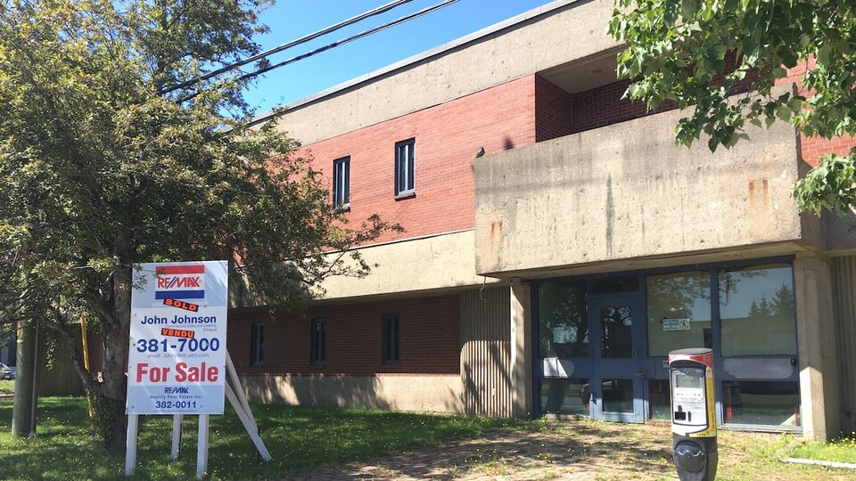 Une enseigne « à vendre » devant l'ancien édifice