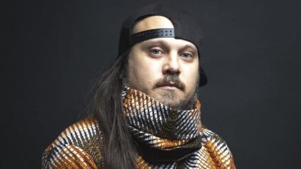 Artist Monk.e poses in a photography studio.