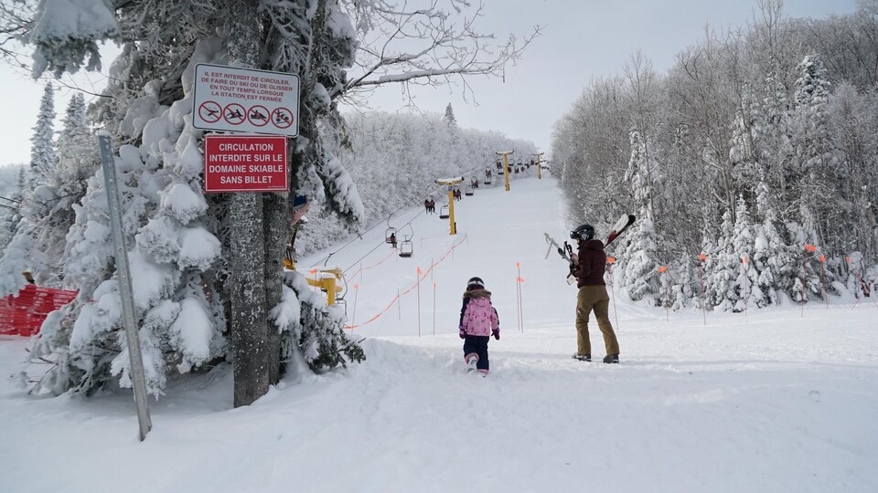 Une femme une fillette amènent leurs skis à l'entrée du parc du Mont-Comi.