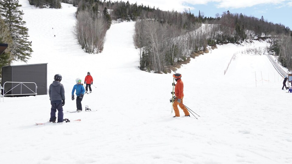 Des skieurs et des planchistes au bas d'une piste de ski. 