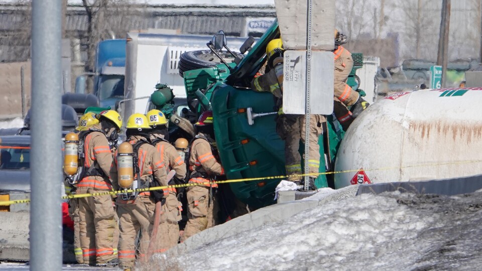 Des pompiers s'affairent à sortir le conducteur de l'habitacle du camion.