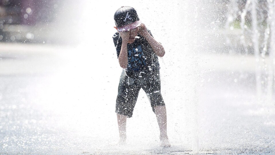 Un enfant s'amuse dans une fontaine.