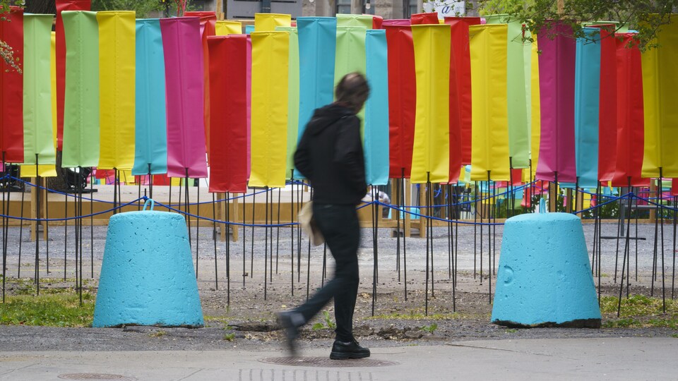Un homme marche près de panneaux verticaux colorés.