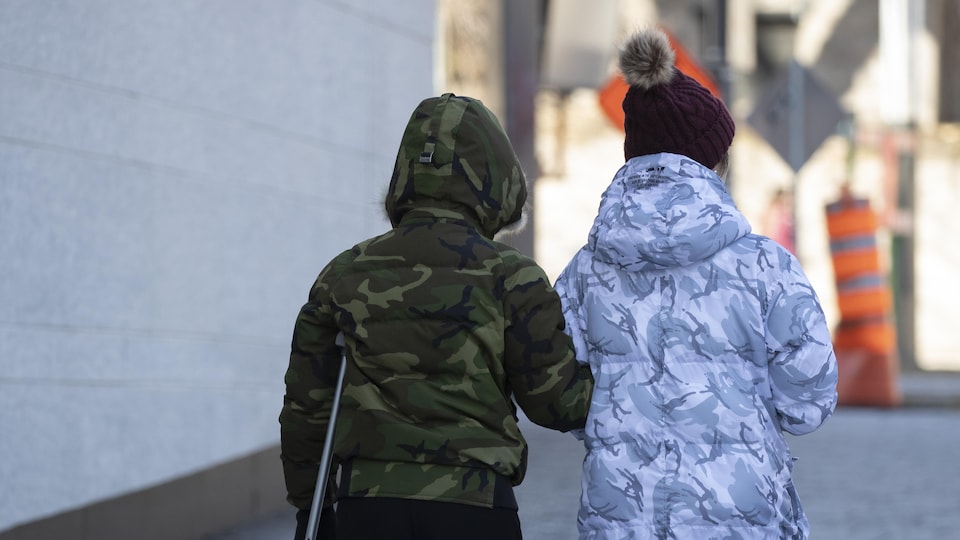 Deux personnes marchent sur un trottoir.