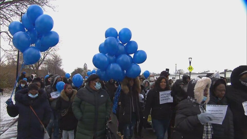 Des marcheurs portant des ballons bleus. 