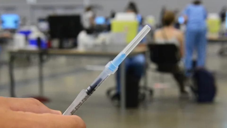 Une main tient une seringue dans un centre de vaccination.
