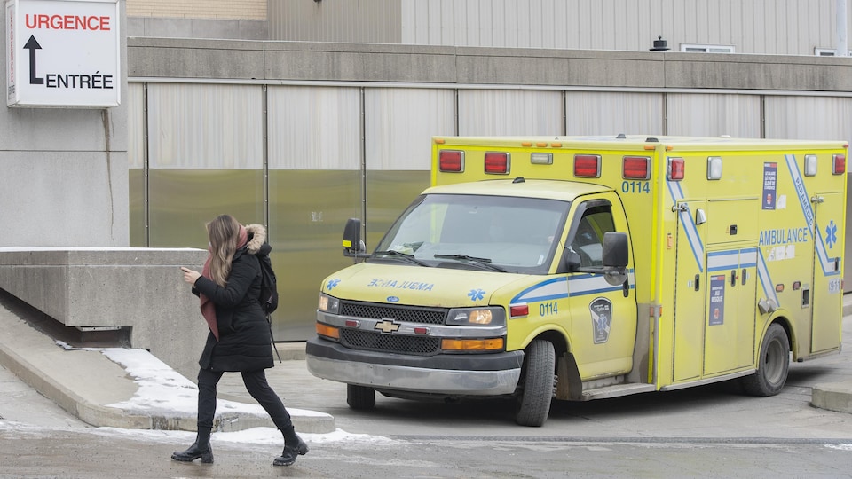 Une femme passe devant une ambulance près de l'entrée des urgences d'un hôpital.