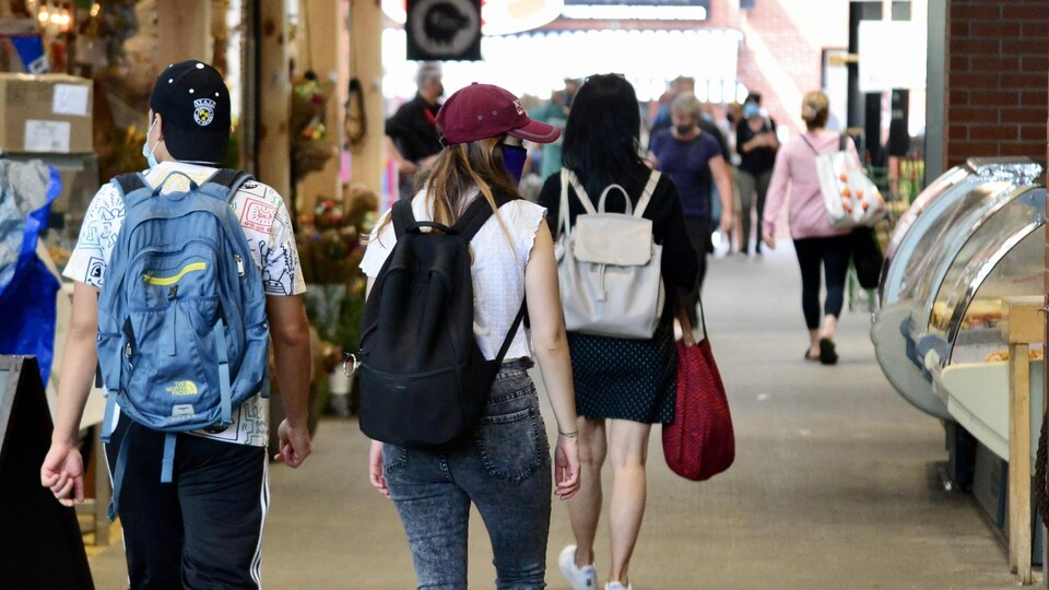 Des personnes portant un masque déambulent dans un marché public.