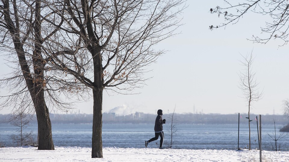 Une personne fait son jogging dans un parc le long du fleuve Saint-Laurent.