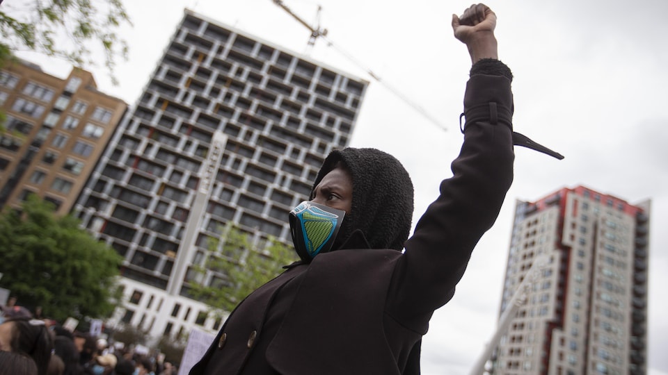 Un manifestant portant un masque et avec le poing gauche en l'air.
