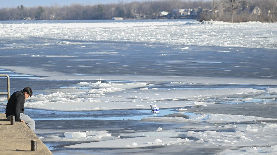 Une personne regarde le canal à Sainte-Anne-de-Bellevue, au Québec, à l'ouest de Montréal, le dimanche 3 mars 2024, par une douce journée d'hiver.
