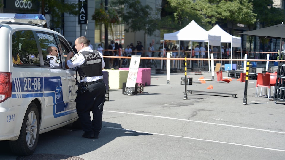Un policier du SPVM accoudé à une fourgonnette de la police.