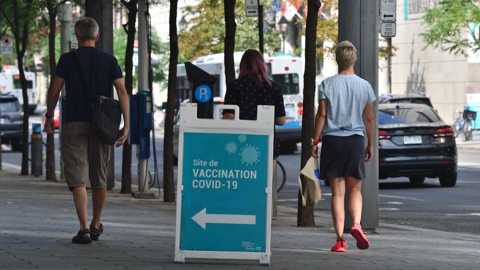 Des gens passent devant l'entrée d'une clinique de vaccination de Montréal.