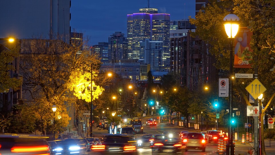 En haut, on voit des gratte-ciel de Montréal et de bas, des voitures circulent dans la nuit.