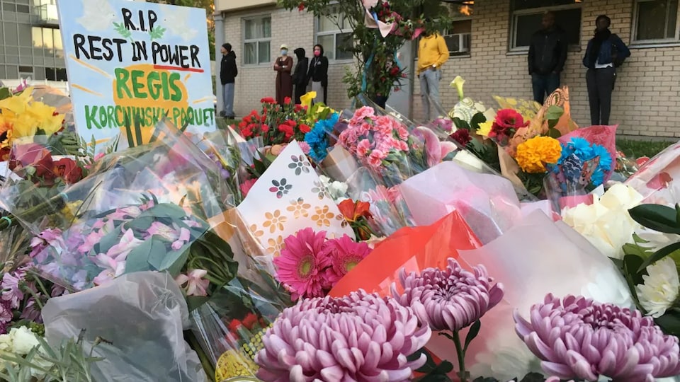 Des gerbes de fleurs près d'une pancarte en l'honneur de la défunte. 