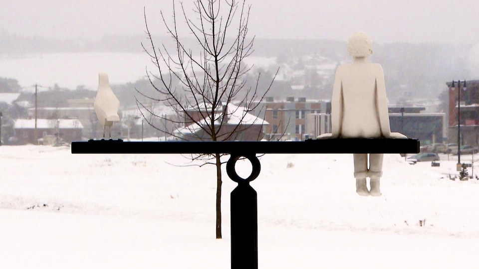 Un monument représentant un enfant et un oiseau regardant au loin.