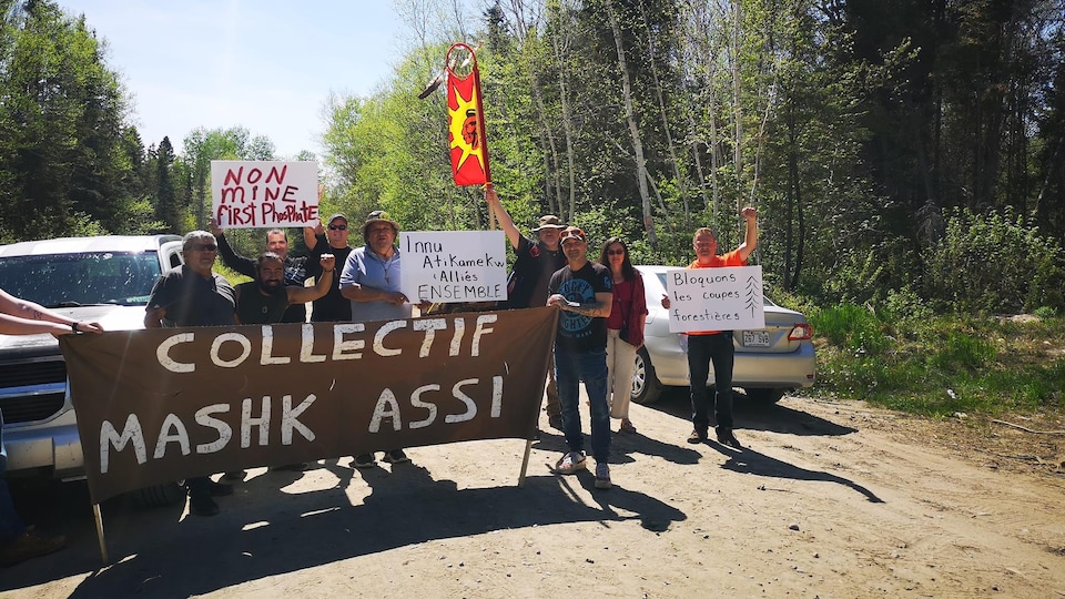 Activists with banners block a logging road.