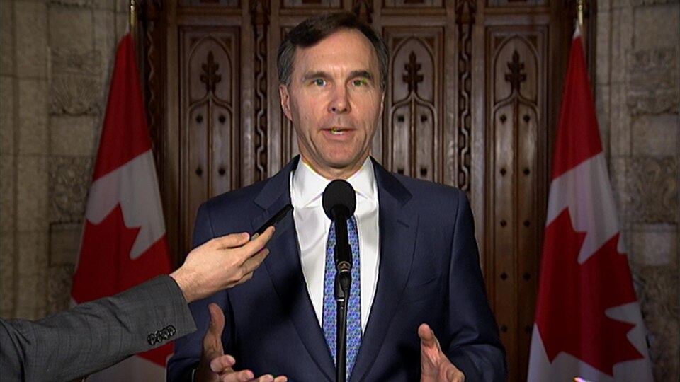 Le ministre des Finances Bill Morneau est debout derrière un microphone lors d'un court point de presse mardi.