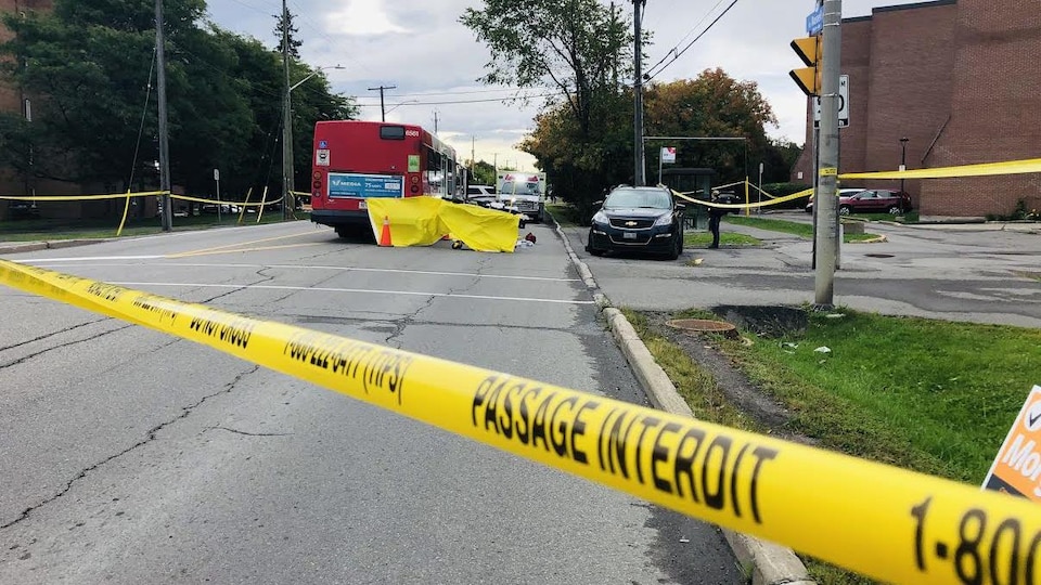 Un autobus, des ambulances et un périmètre de sécurité entourant les lieux d'un accident.