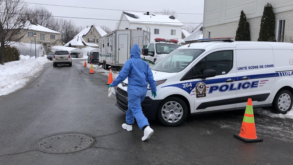 Plusieurs véhicules de police sont stationnés autour de la maison.
