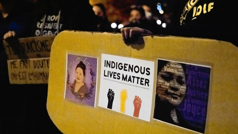 Une personne tient entre les mains une pancarte sur laquelle est écrit en anglais « indigenous lives matter ».