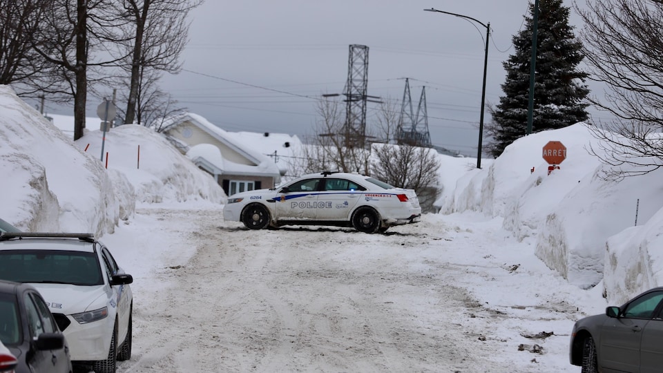 Une voiture de police est stationnée en travers d’une rue dans un quartier résidentiel de Val-Bélair.