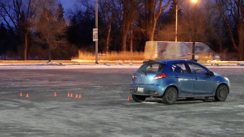 Une petite voiture seule au milieu d'un stationnement.