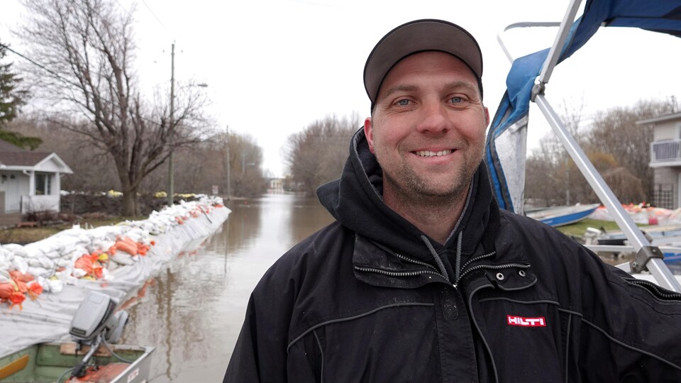 M. Chartrand sourit à la caméra sur une rue inondée.
