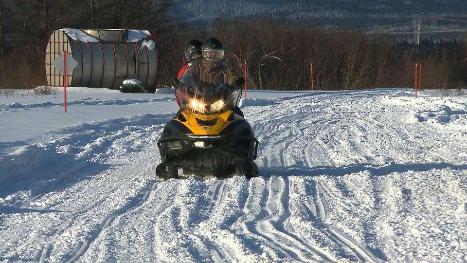 Deux amateurs en motoneige sur une piste balisée