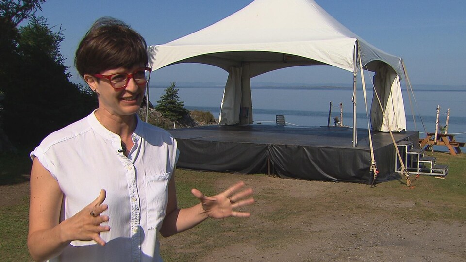Karine Vincent accorde une entrevue à Radio-Canada devant une scène extérieure près de l'eau.