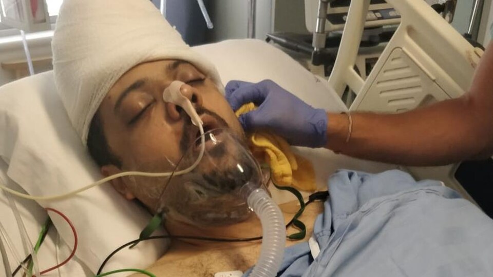 Photo d'un homme couché dans un lit d'hôpital et branché à un respirateur