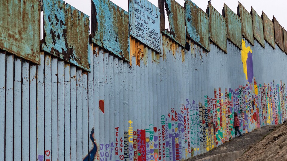 TOPSHOT - A girl travelling in a caravan of Central American migrants hoping to reach the United States, looks through the US-Mexico border fence in Playas de Tijuana, Baja California State, Mexico, on December 14, 2018. - A seven-year-old Guatemalan girl died of dehydration and exhaustion in the custody of US border agents last week, on December 8, as President Donald Trump struggles to deter a tide of migrants fleeing poverty and violence in Central America -- and battles with Congress for a