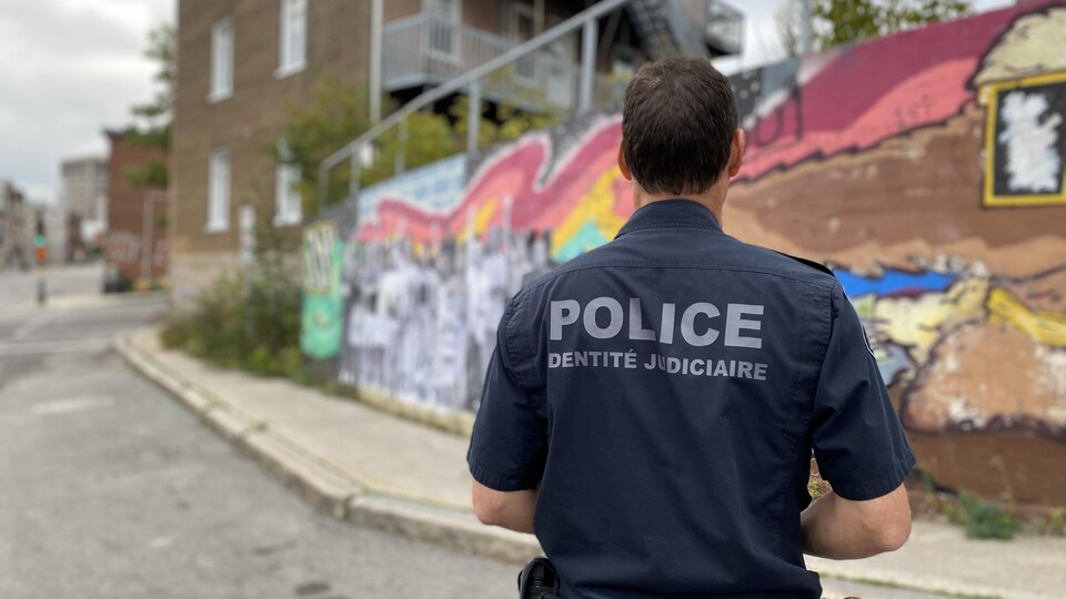 Un policier se tient devant la murale.