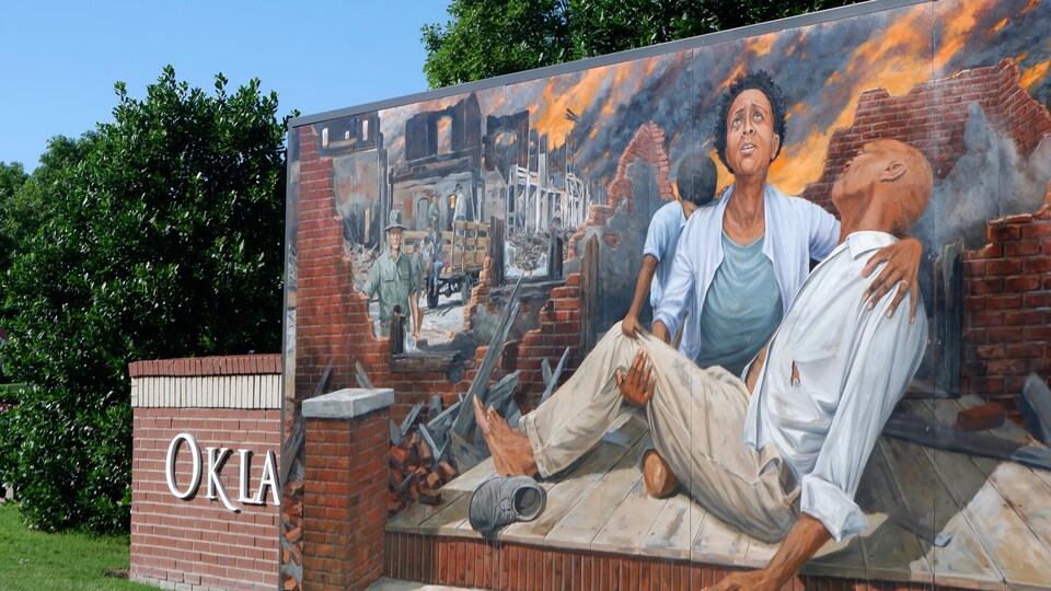Une personne secourue et des bâtiments en feu sont peints sur un mur.