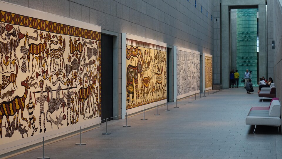 Un couloir orné de grandes murales peintes. 
