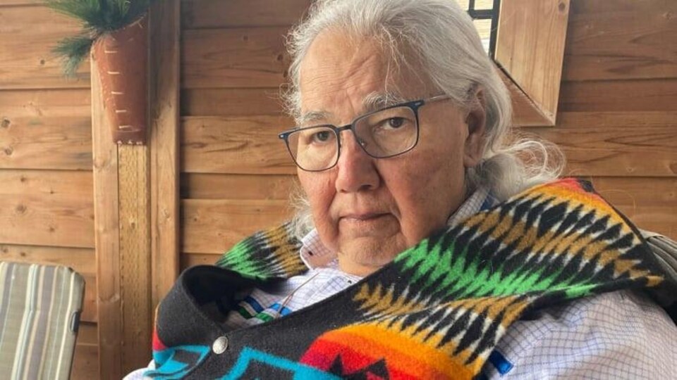 Murray Sinclair photogaphié dans une pièce aux murs en bois.